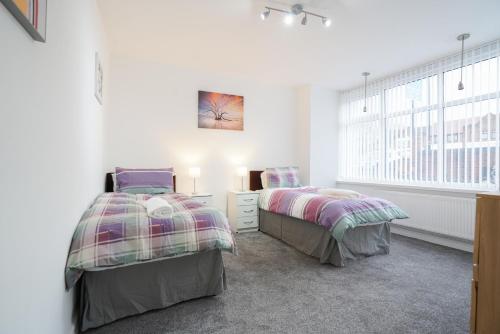 two beds in a room with white walls and a window at BIRMINGHAM HAGLEY WEST HOUSE, 5 bedrooms with 7 BEDS, 3x doubles beds, 4x singles beds,2 toilets,2 bathrooms,2 toilets, sleeps 7-10 people great motorway links M5 M6 M42 A38 A34 in Birmingham