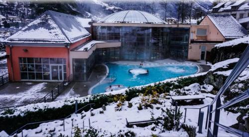 a building with a swimming pool in the snow at Studio idéalement situé in Cauterets