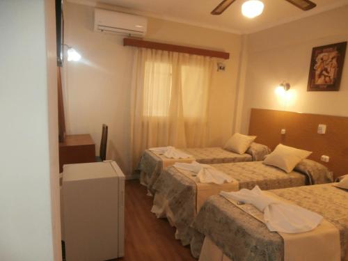 a hotel room with three beds and a television at Hotel Alma di Mare in Mar del Plata