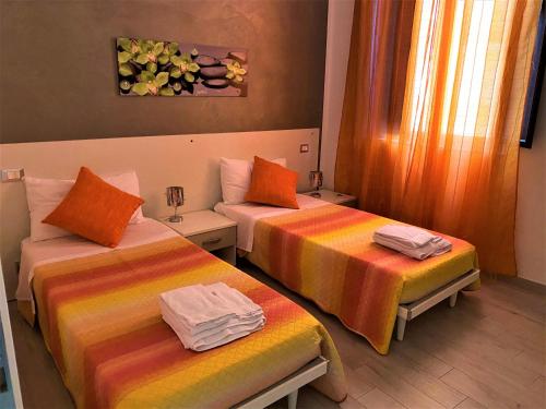 トラーパニにあるLe casette del generaleのカラフルなシーツを使用したベッド2台が備わるホテルルームです。