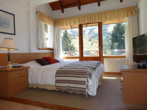 a bedroom with a bed and a large window at Hotel Punta Condor in San Carlos de Bariloche