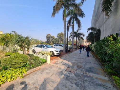 a group of people walking down a sidewalk with palm trees at The Heritage Villa in Patiāla