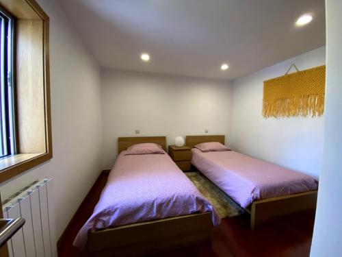 two beds in a bedroom with purple sheets at Casa Vale da Cortinha - Near Gerês in Vieira do Minho
