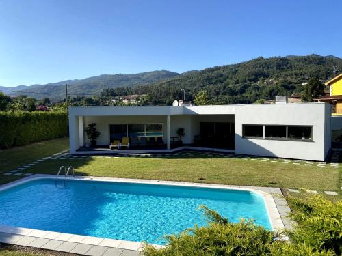 a villa with a swimming pool in front of a house at Casa Vale da Cortinha - Near Gerês in Vieira do Minho