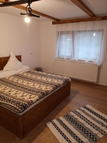 a bedroom with a bed and a window and two rugs at Casa Livada Bunicii in Târgu Ocna