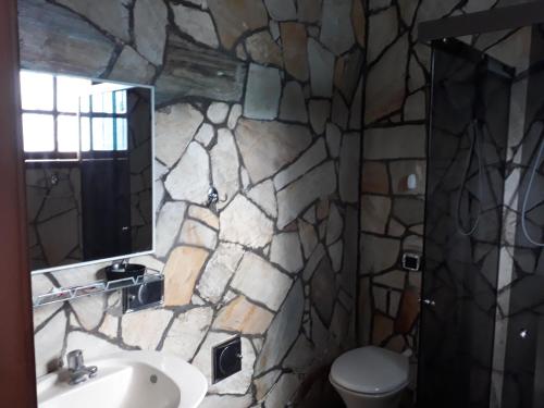 a stone bathroom with a sink and a toilet at Itaúna Hostel in Saquarema