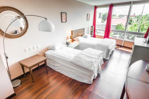 Habitación de hotel con 2 camas y espejo en Hotel Sarah Nui en Papeete