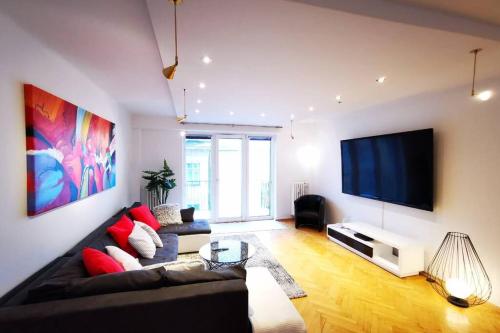 a living room with a couch and a flat screen tv at Charmante Zentrumswohnung mit Balkon und 80 zoll TV in Klagenfurt
