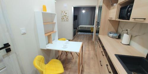 una pequeña cocina con una mesa blanca y sillas amarillas en Apartament CCH - Biskupia, en Chełmno