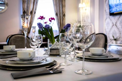 a table with wine glasses and plates and flowers on it at Hotel Madelaine in Lwówek Śląski