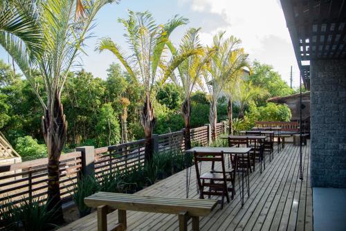 a row of tables and chairs on a deck with palm trees at Pousada Cabanas Kaia Lua in Praia do Rosa