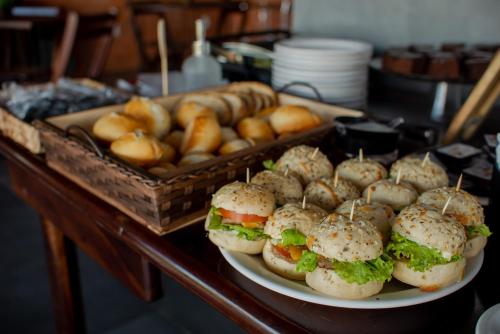a plate of sandwiches and rolls on a table at Pousada Cabanas Kaia Lua in Praia do Rosa
