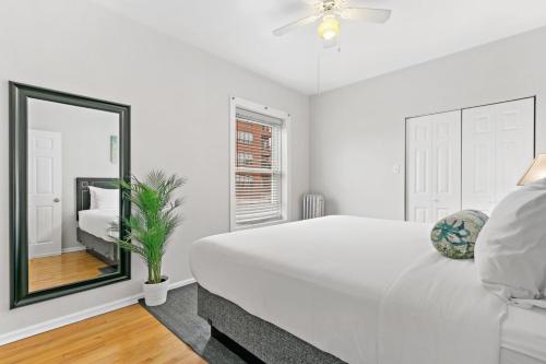 a white bedroom with a large white bed and a mirror at 1BR Apartment in Rogers Park with King Bed - Lunt 2E in Chicago