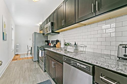 a kitchen with black cabinets and stainless steel appliances at 1BR Apartment in Rogers Park with King Bed - Lunt 2E in Chicago