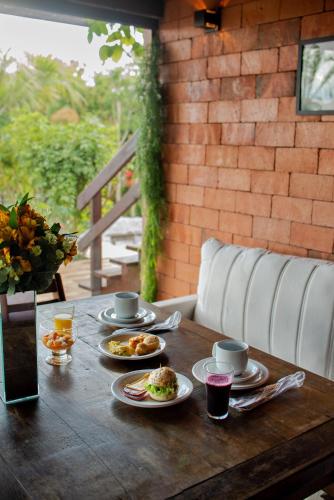 a wooden table with plates of food on it at Pousada Cabanas Kaia Lua in Praia do Rosa