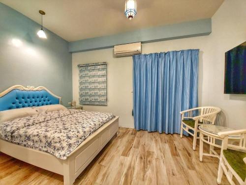 1 dormitorio con 1 cama y una ventana con cortinas azules en 出門獺踏 Otter footprints B&B, en Jinsha