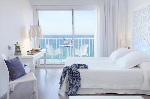 a bedroom with a bed and a desk and a balcony at Hotel Planamar by Escampa Hotels in Platja d'Aro