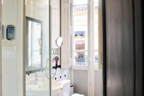 a bathroom with a sink and a toilet and a window at TOULOUSAINE DE STANDING - GARAGE - COUR - CINEMA in Toulouse