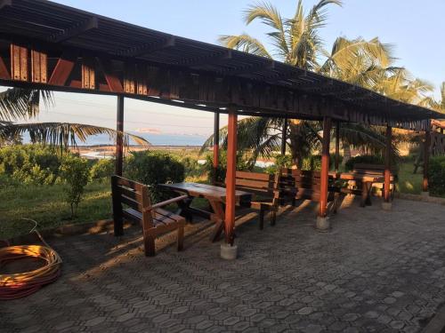 a picnic shelter with benches and a view of the ocean at beach front stephen's house in Inchaban