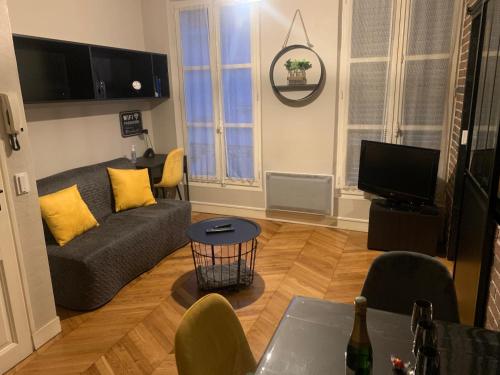 a living room with a couch and a tv at Appartement centre Fontainebleau in Fontainebleau