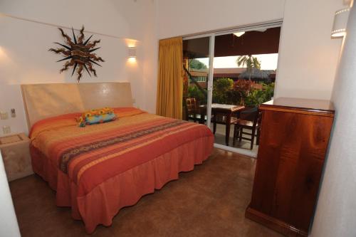 a bedroom with a bed and a table and a window at La Ceiba del Mar in Zihuatanejo
