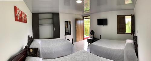1 dormitorio con 2 camas con sábanas blancas y ventana en Finca El Bazar en Montenegro