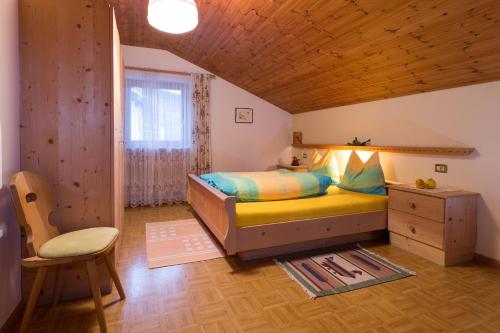 a bedroom with a bed and a chair and a window at Ferienwohnungen Parth in Lasa