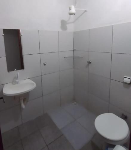 a white bathroom with a toilet and a sink at Pouso D' Braga in Pirenópolis