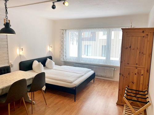 a bedroom with a bed and a table and a window at Zentrale gemütliche Wohnung St Moritz - A212 in St. Moritz