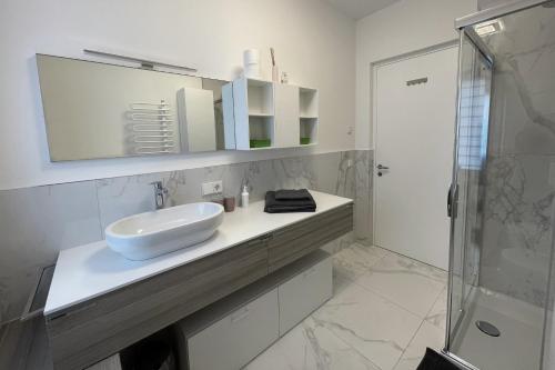 a white bathroom with a sink and a shower at Apartments Griesser in Bressanone