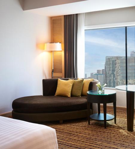 a hotel room with a couch and a large window at Amari Bangkok in Bangkok