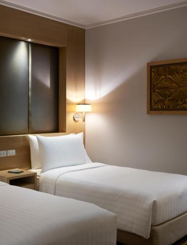 a hotel room with two beds and a window at Amari Bangkok in Bangkok