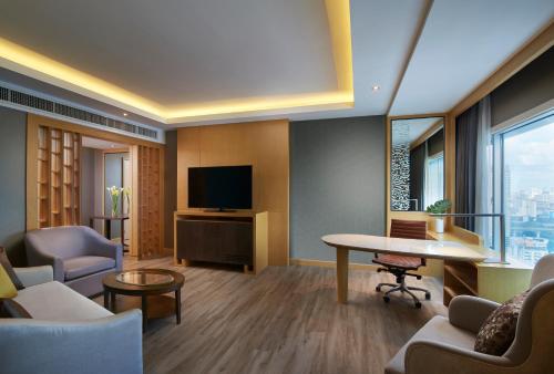 a living room with a tv and a table and chairs at Amari Bangkok in Bangkok