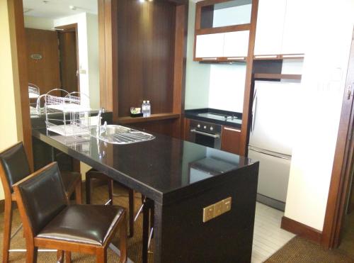 a kitchen with a black counter and some chairs at St Giles Gardens Kuala Lumpur in Kuala Lumpur