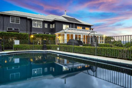 a house with a swimming pool in front of a fence at Black Swan Lakeside Boutique Hotel in Rotorua