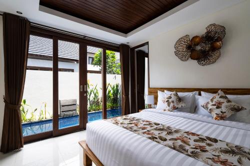 The Calna Villa Bali في كوتا: غرفة نوم بسرير ونافذة كبيرة