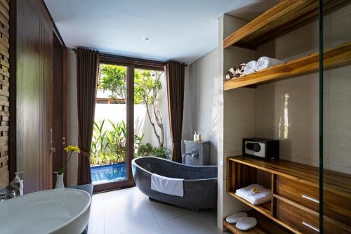 baño con bañera y ventana grande en The Calna Villa Bali, en Kuta