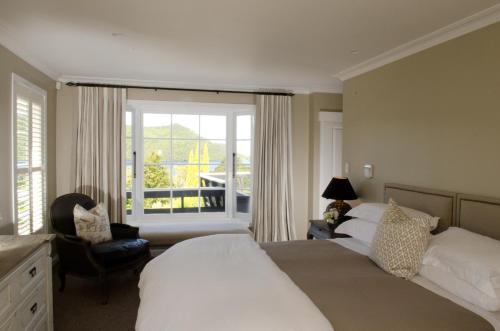 a bedroom with two beds and a chair and a window at Ngamihi Lodge in Rotorua