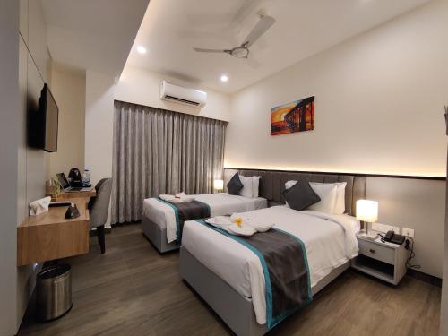 Habitación de hotel con 2 camas y TV en PARK IRIS HOTELS, Bharathi Nagar, en Vijayawāda