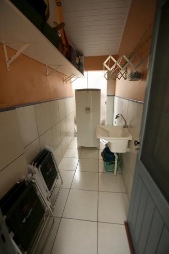 a small bathroom with a sink and a refrigerator at Chalé Rosé in Torres