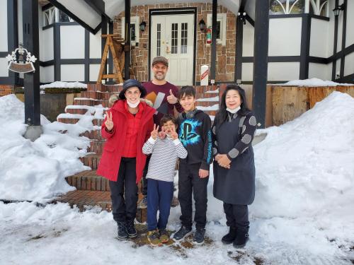 a family posing for a picture in the snow at プチホテル葡萄屋 in Hakuba