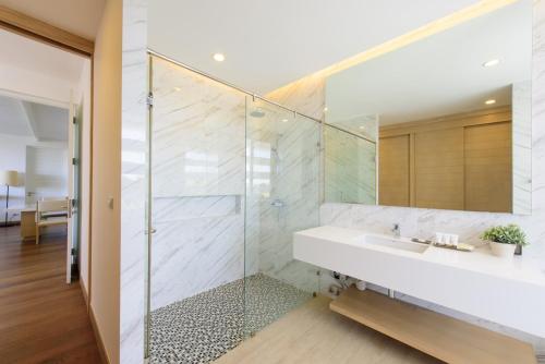 a bathroom with a glass shower and a sink at The Gallery Khao Yai Hotel and Residence - SHA Plus in Khao Yai