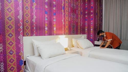a man standing between two beds in a hotel room at Alam Hotel by Cordela in Medan