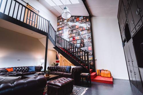 a living room with leather couches and a staircase at Union Street - Central Castlemaine Pad in Castlemaine