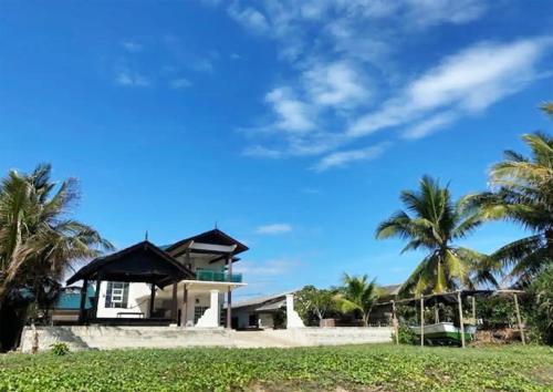 a house on the beach with palm trees at CoLiving CHE Beach House by Vale Pine in Kuala Terengganu