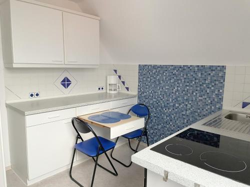 una cocina con armarios blancos y sillas azules. en Fewo Haus Piepenbreier, en Bad Sassendorf