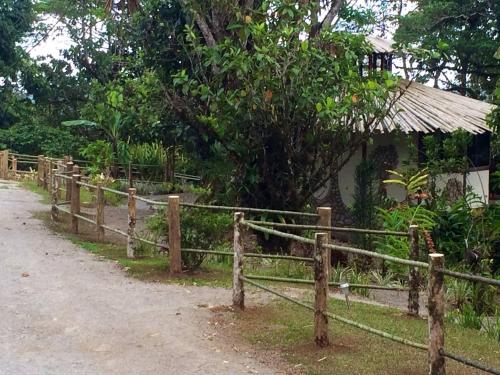 a fence in front of a house next to a road at Cascata Del Bosco Cabinas in San Vito