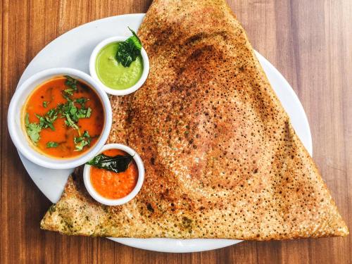 a white plate with two pieces of chapati and two sauces at Shila International in Kolkata