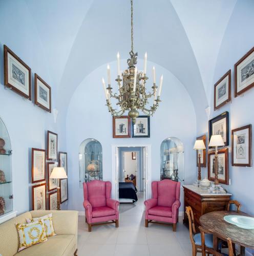 a living room with pink chairs and a chandelier at The Tsitouras Collection in Firostefani