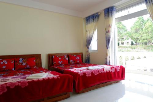 a bedroom with two beds with red sheets and a window at Tuan Vu Hai Dang Da Lat in Da Thanh